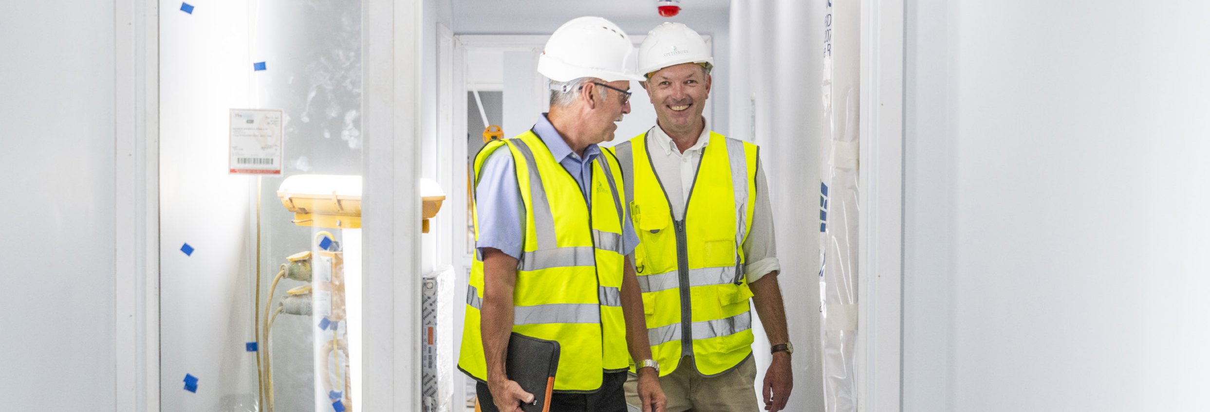 Spetisbury Construction team members indoors wearing hard-hats and high-vis vests.