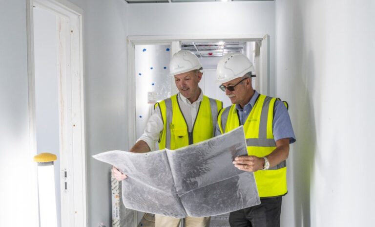 Spetisbury Construction team looking at building plans, wearing hard-hats and high-vis vests.